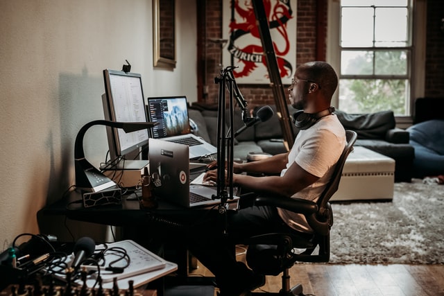 man achter beeldschermen computer