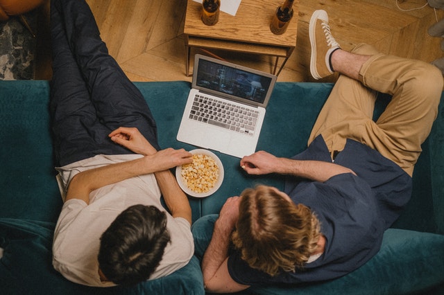 mannen kijken film op laptop met popcorn